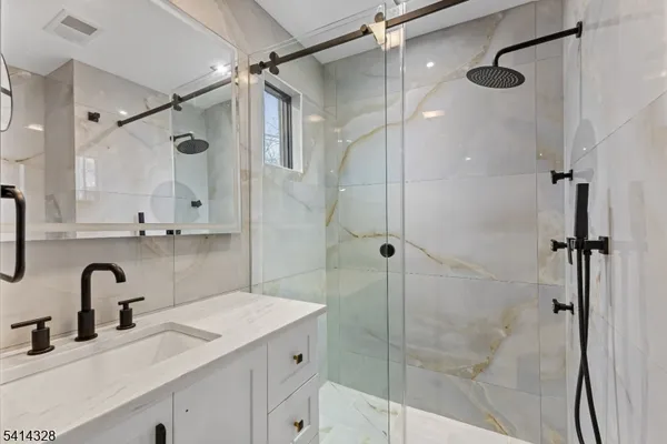 a bathroom with a shower sink vanity and mirror