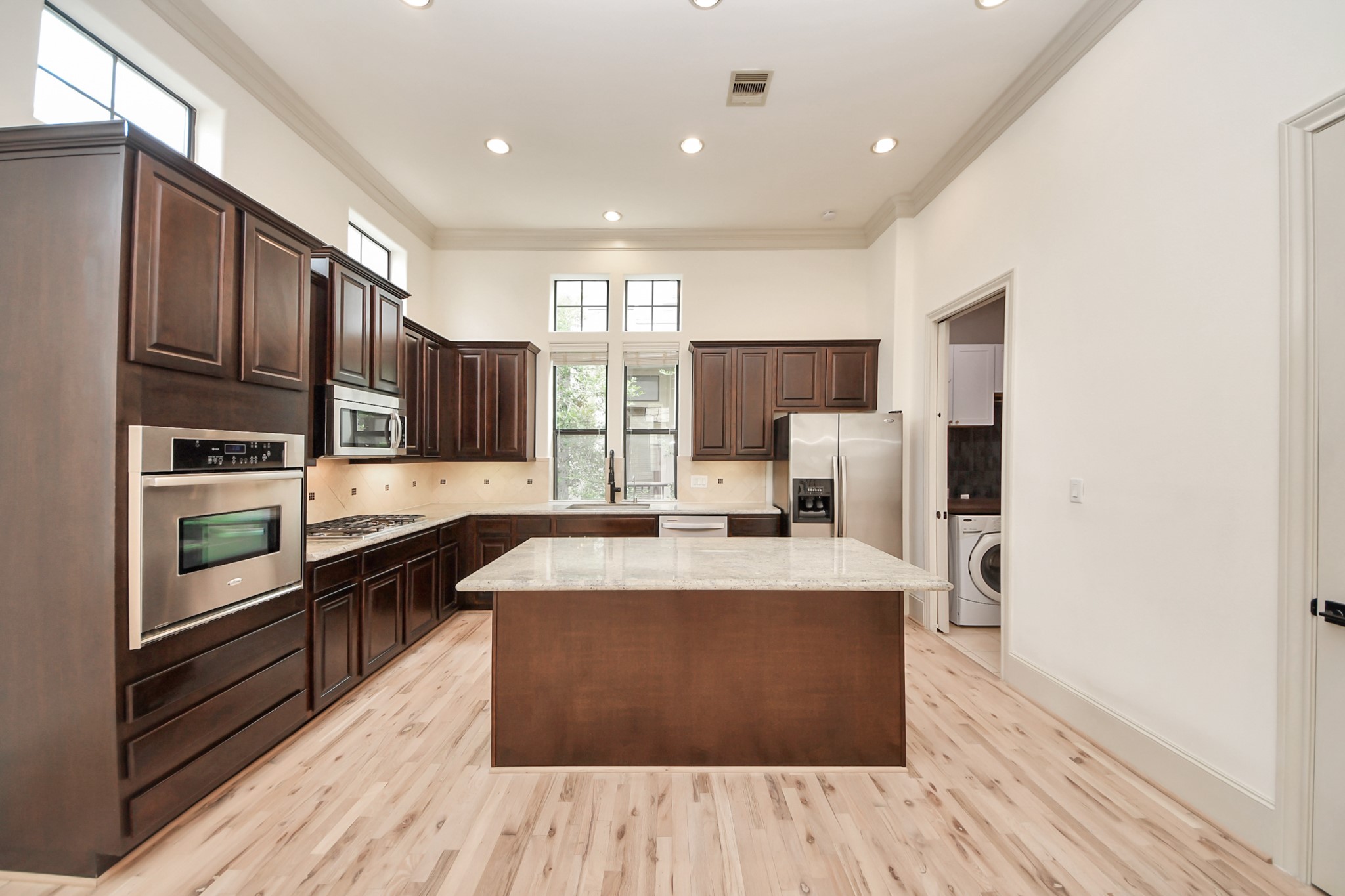 3229 Maxroy Street Houston, TX 77008 - Photo 22 of 43 A spacious kitchen equipped with stainless steel appliances, a gas cooktop, rich dark cabinets, and a large central island with granite countertops.