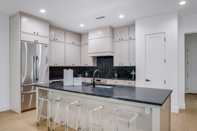 3601 Routh Street, Unit 2E Dallas, TX 75219 - Photo 5 of 14 Kitchen with high quality fridge, backsplash, a sink, light wood finished floors, and dark stone countertops