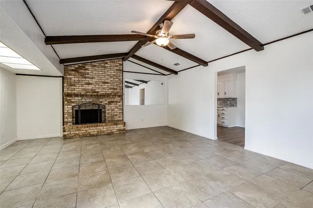 a view of an empty room with a fireplace and a ceiling fan