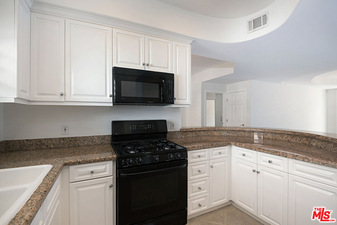 4400 Cartwright Avenue, Unit 201 Toluca Lake, CA 91602 - Photo 8 of 30 a kitchen with granite countertop white cabinets and black appliances