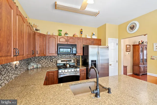 a kitchen with stainless steel appliances kitchen island granite countertop a refrigerator and a stove top oven