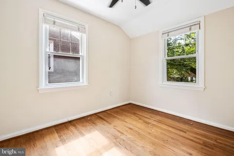 a view of empty room with window and wooden floor