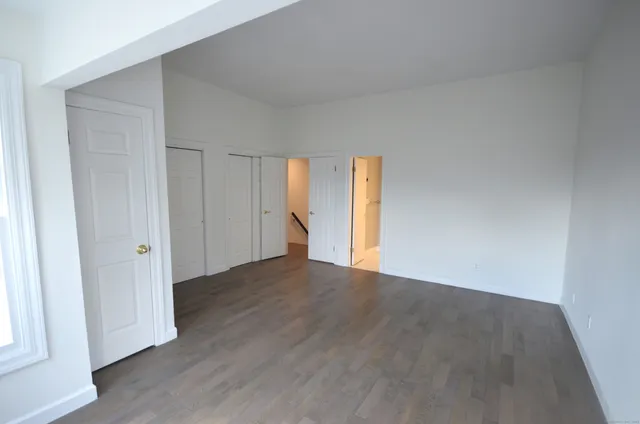 a view of an empty room with wooden floor and window