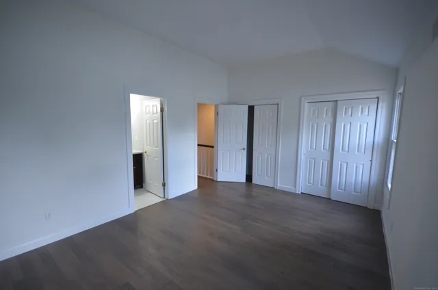 a view of an empty room with closet and wooden floor