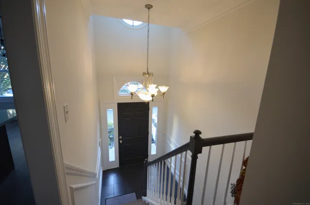 a view of a hallway with wooden floor and chandelier