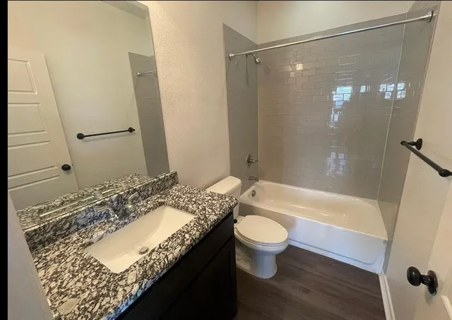 a bathroom with a granite countertop sink toilet and shower