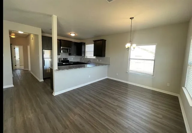 a view of a kitchen and an empty room with wooden floor