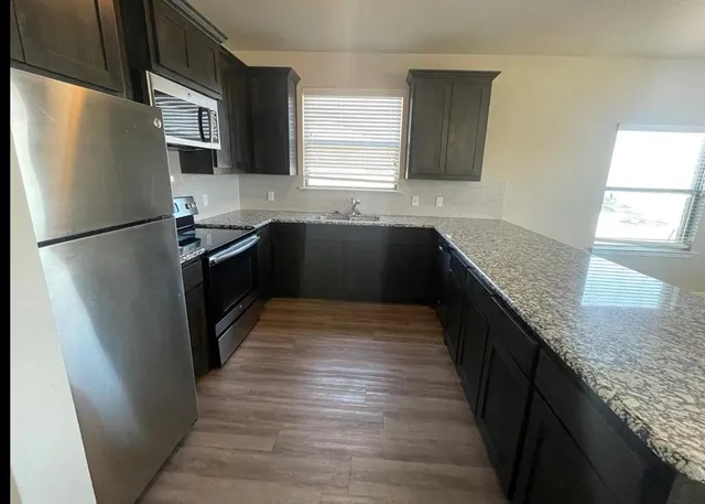 a kitchen with granite countertop a refrigerator and a sink