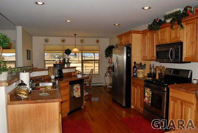 1677 P Road Loma, CO 81524 - Photo 4 of 14 a kitchen with stainless steel appliances granite countertop a refrigerator a stove top oven a sink dishwasher and wooden cabinets with wooden floor