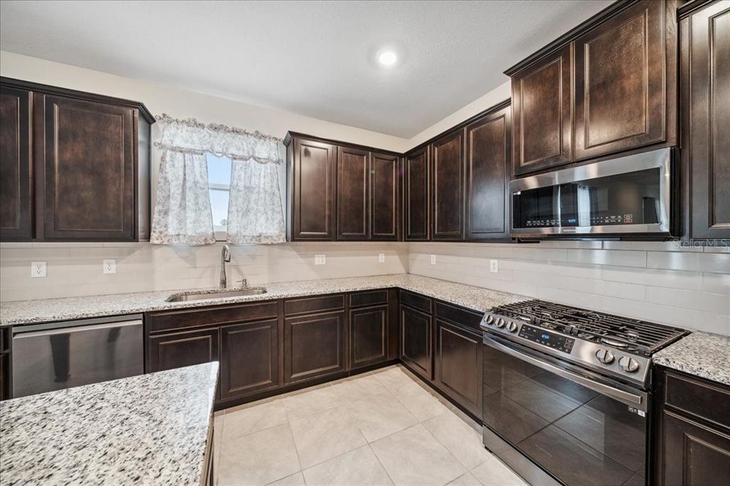 8110 Southwest 59th Terrace Ocala, FL 34476 - Photo 12 of 35 a kitchen with stainless steel appliances granite countertop a sink stove and microwave
