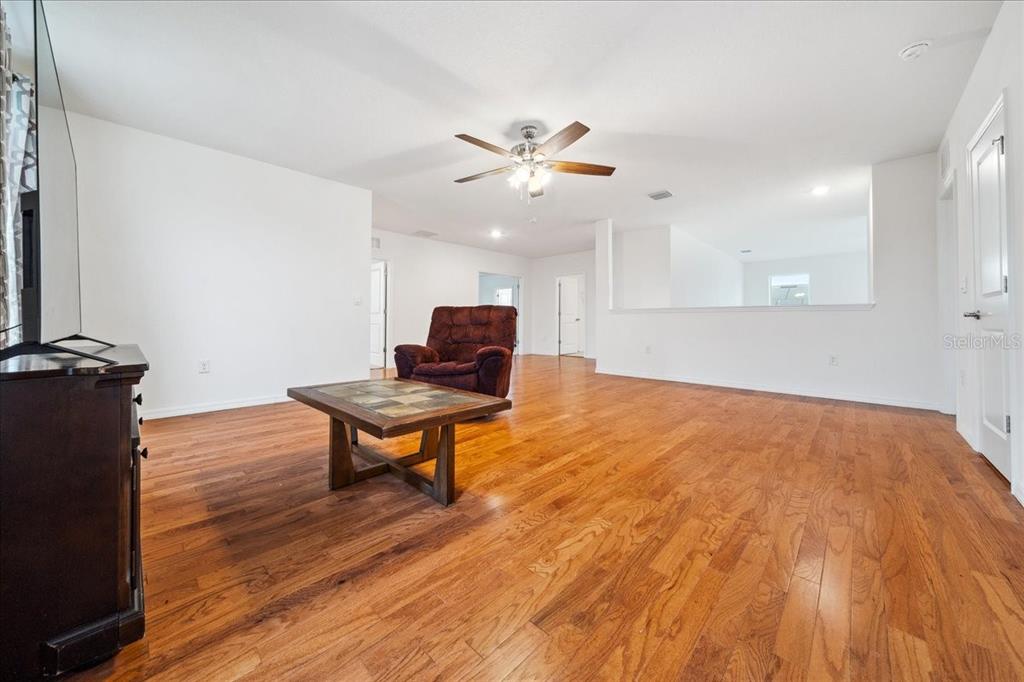 8110 Southwest 59th Terrace Ocala, FL 34476 - Photo 20 of 35 a living room with kitchen island wooden floor and a ceiling fan