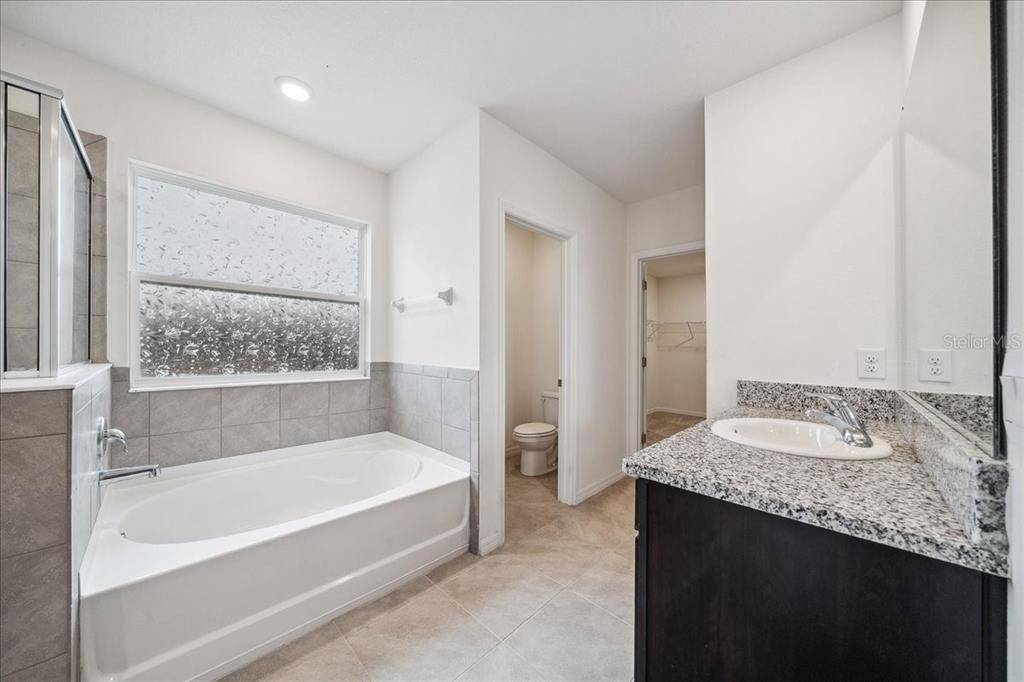8110 Southwest 59th Terrace Ocala, FL 34476 - Photo 23 of 35 a spacious bathroom with a granite countertop tub sink and mirror
