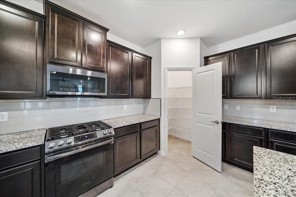 8110 Southwest 59th Terrace Ocala, FL 34476 - Photo 10 of 35 a kitchen with granite countertop stainless steel appliances and wooden cabinets