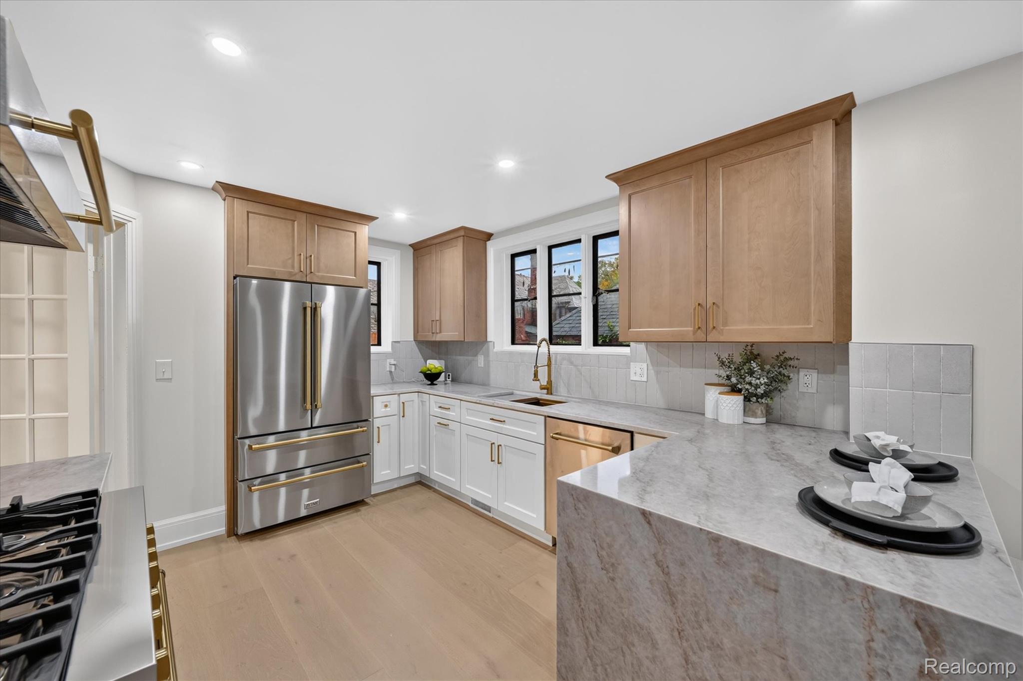 3250 Sherbourne Road Detroit, MI 48221 - Photo 14 of 36 Stainless steel appliances, wood-finish flooring, white and natural wood cabinetry, light-toned countertops, and a tiled backsplash