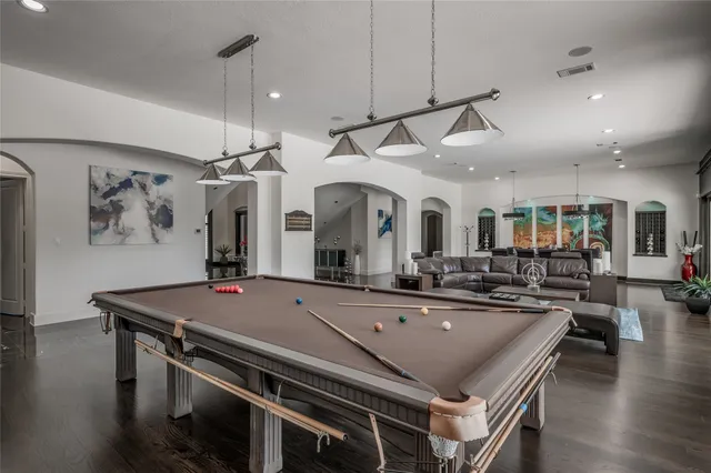 a kitchen with granite countertop a stove a sink dishwasher a dining table and chairs with wooden floor