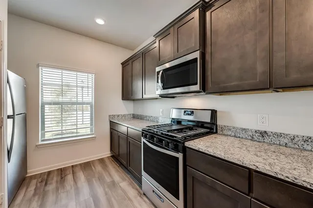 a kitchen with granite countertop wooden cabinets stove top oven and sink
