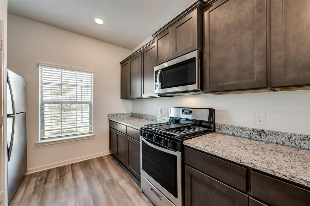 8126 Big Timber Trail Ponder, TX 76259 - Photo 5 of 16 a kitchen with granite countertop wooden cabinets stove top oven and sink