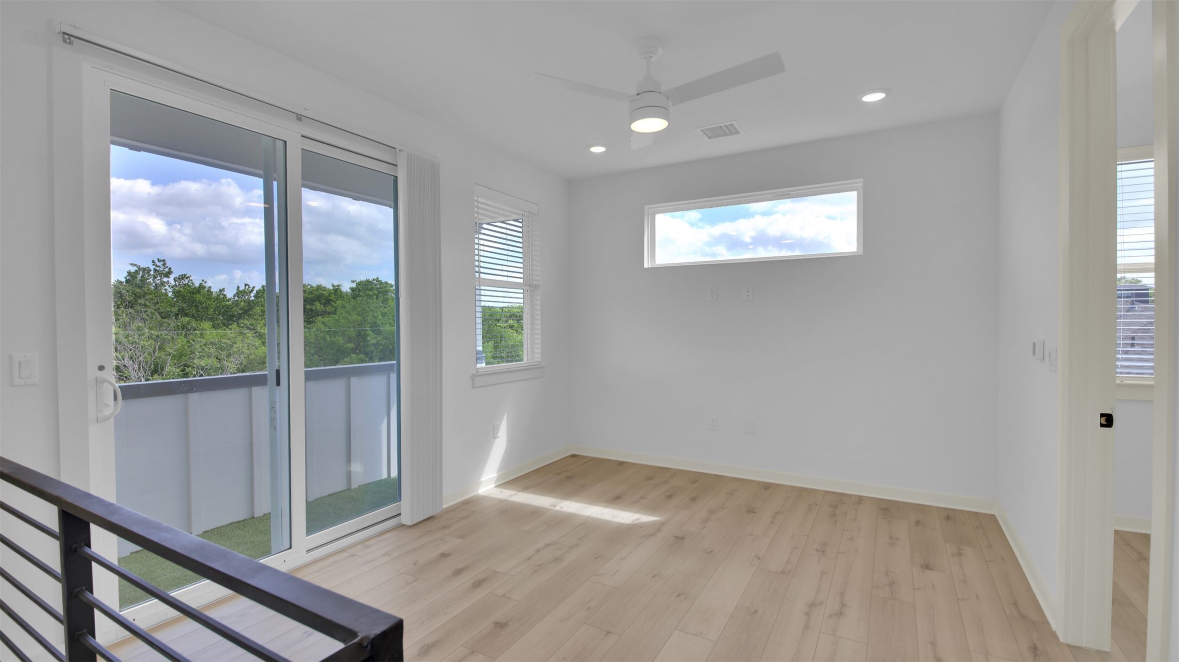 7208 Providence Avenue, Unit 1 Austin, TX 78752 - Photo 19 of 26 Spacious room featuring light-toned flooring, a modern ceiling fan, recessed lighting, and large sliding glass doors leading to a balcony