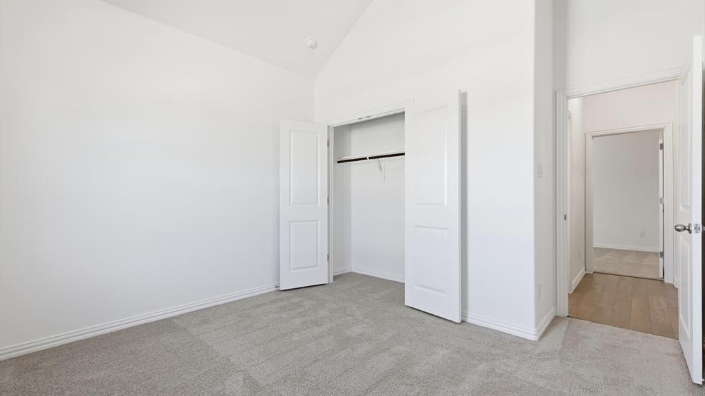 2529 Rivers W Road Anna, TX 75409 - Photo 11 of 40 Room featuring a vaulted ceiling, light gray carpet flooring, white baseboards, and a bi-fold closet with a hanging rod