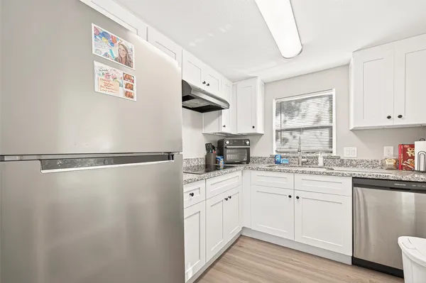 a kitchen with a white cabinets a sink dishwasher and a stove with wooden floor