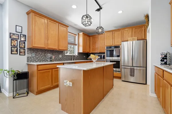 a kitchen with stainless steel appliances granite countertop a refrigerator a sink dishwasher a stove and a refrigerator with wooden cabinets