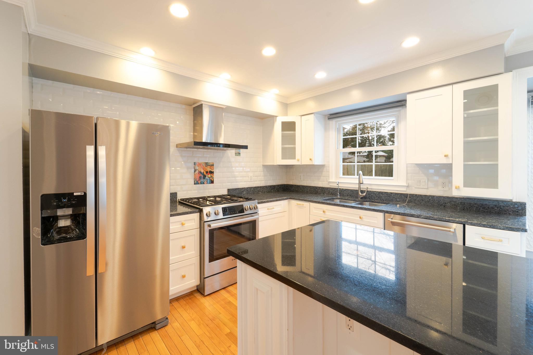 9407 Copernicus Drive Lanham, MD 20706 - Photo 9 of 48 a kitchen with stainless steel appliances granite countertop a refrigerator a stove and a sink with wooden floor