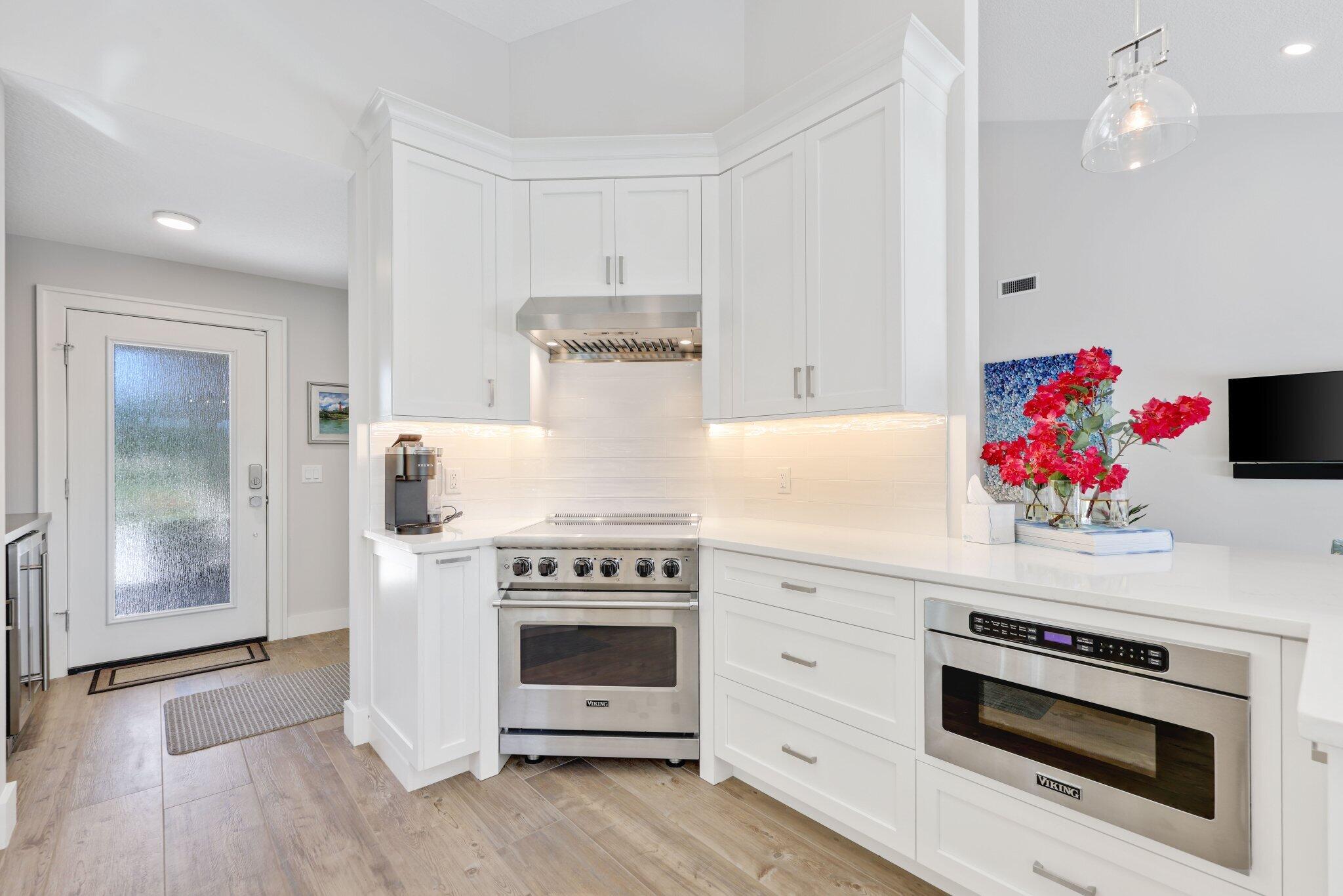 215 Ridge Road Jupiter, FL 33477 - Photo 12 of 43 a kitchen with a stove and white cabinets with wooden floor