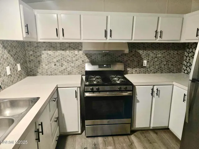 a view of a refrigerator in kitchen with stainless steel appliances wooden floor