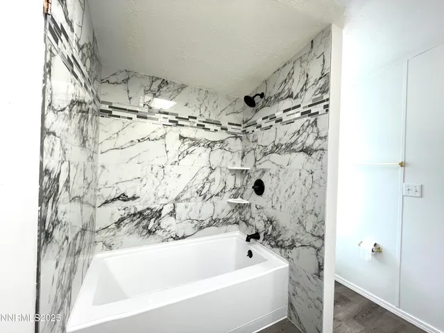 a view of a hallway with wooden floor and a bathroom