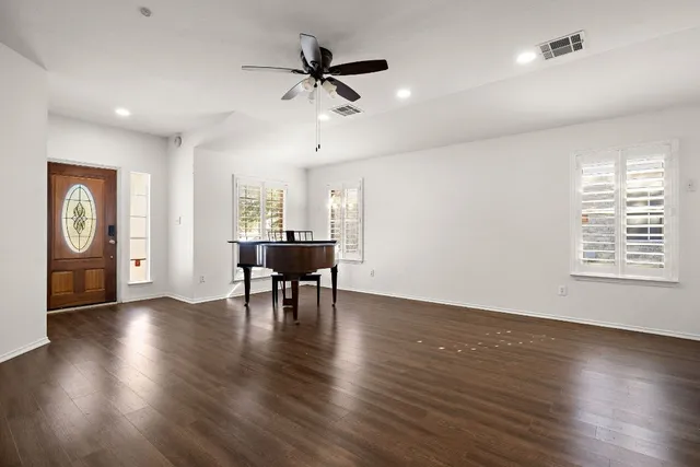 a view of an empty room with a window and wooden floor