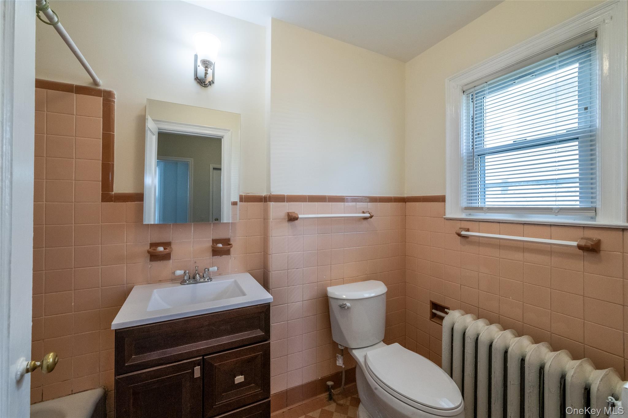 7 Alpha Place, Unit FIRST New Rochelle, NY 10805 - Photo 13 of 25 Full bath with radiator heating unit, vanity, tile walls, and a wainscoted wall