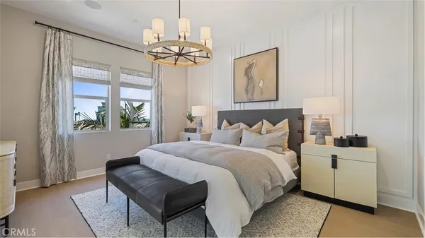 a bedroom with a bed a chandelier and mirror on the dresser