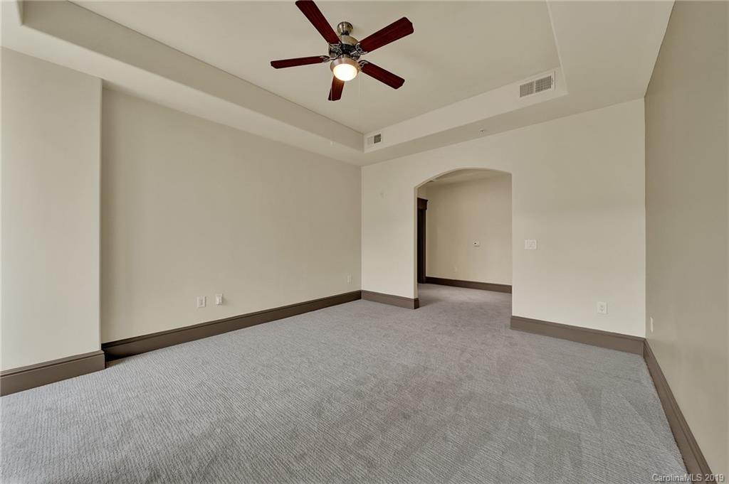 4300 Sharon Road, Unit 404 Charlotte, NC 28211 - Photo 9 of 10 an empty room with a ceiling fan and carpet