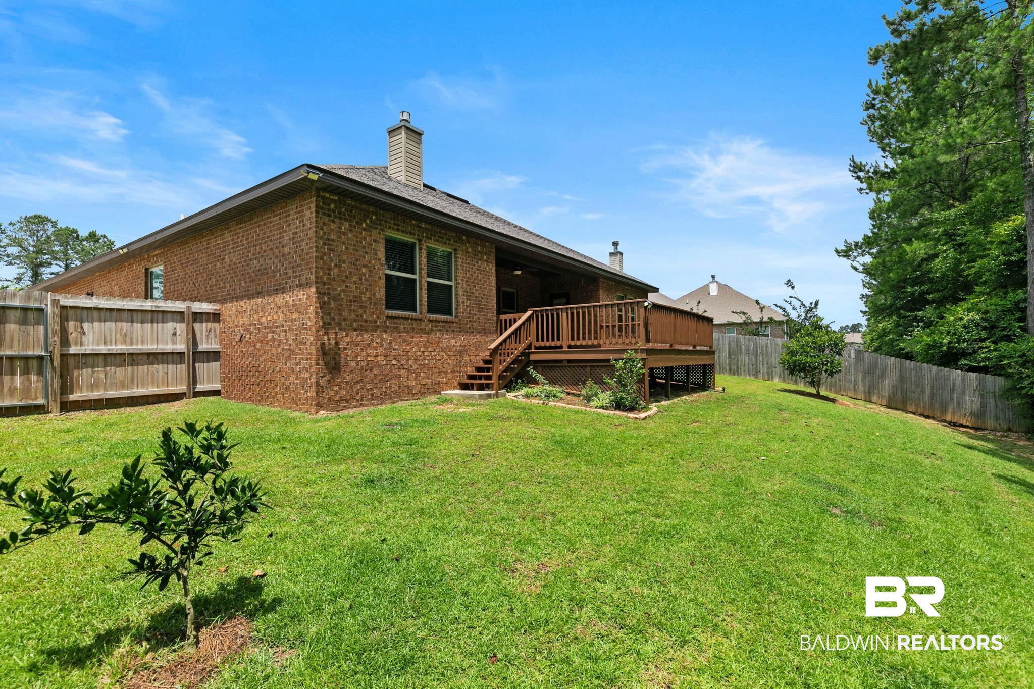 31350 Hoot Owl Road Daphne, AL 36527 - Photo 92 of 94 Rear exterior featuring a wood-finish deck with stairs, brick siding, and a fenced perimeter