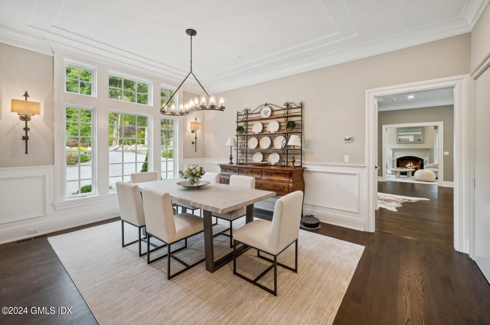 155 Cat Rock Road Cos Cob, CT 06807 - Photo 6 of 29 a dining room with wooden floor a chandelier a wooden table and chairs