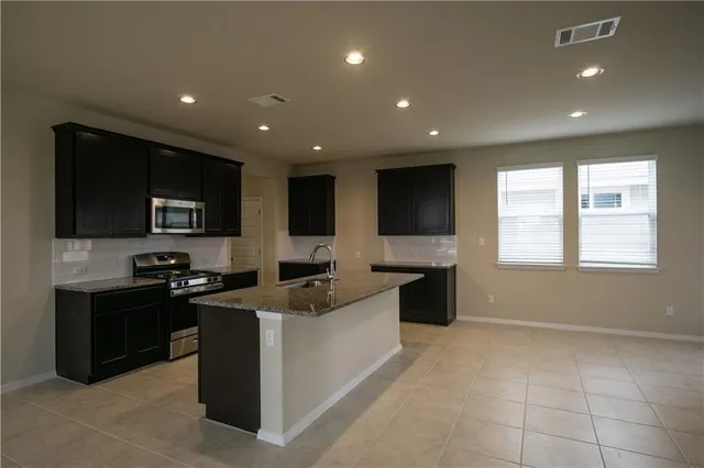 a large kitchen with stainless steel appliances granite countertop a large counter top and a stove top oven