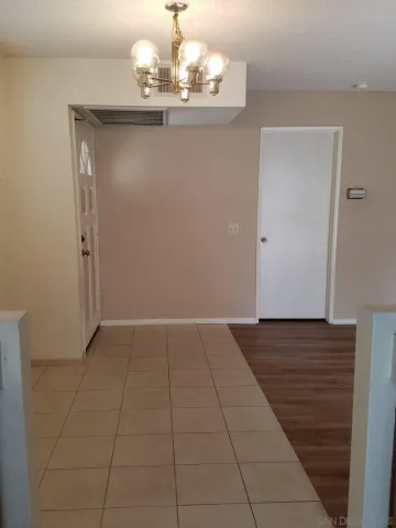 a view of an empty room with wooden floor and a chandelier