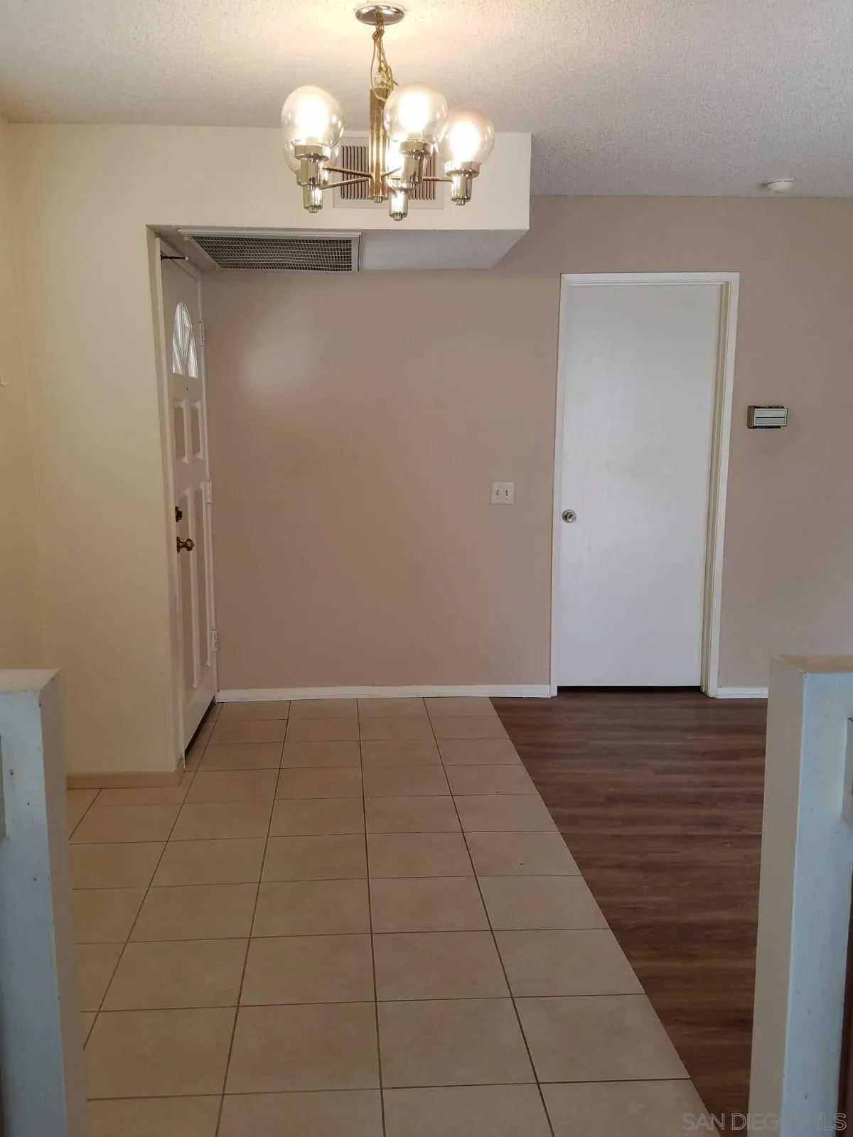 13294 Wimberly Square, Unit 228 San Diego, CA 92128 - Photo 3 of 24 a view of an empty room with wooden floor and a chandelier