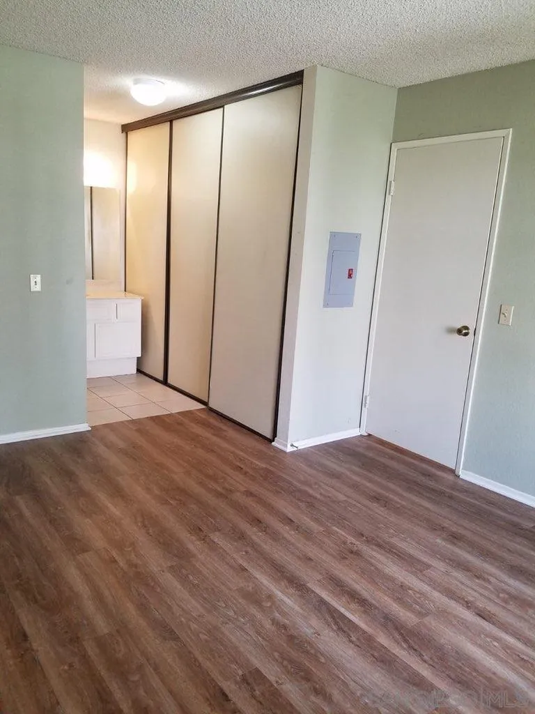 13294 Wimberly Square, Unit 228 San Diego, CA 92128 - Photo 8 of 24 an empty room with wooden floor and mirror