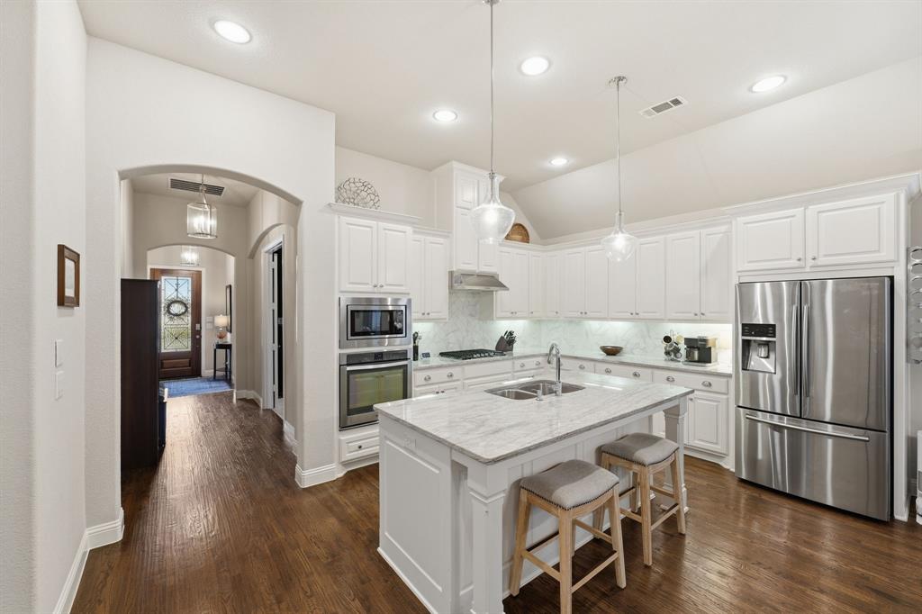 5105 Ember Place Little Elm, TX 76227 - Photo 8 of 35 a kitchen with a center island wooden floor and stainless steel appliances