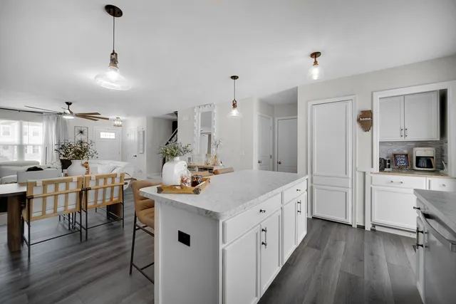a kitchen with kitchen island granite countertop lots of white cabinets appliances and furniture