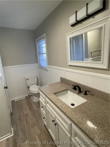 a bathroom with a granite countertop sink a toilet and mirror
