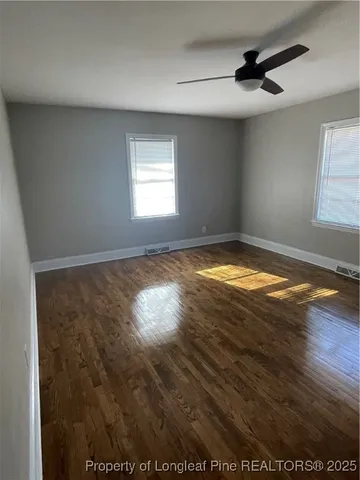 a view of empty room with wooden floor and fan