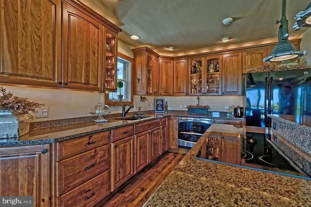a kitchen with granite countertop a stove a sink a dining table and chairs