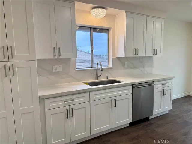 a kitchen with white cabinets and sink