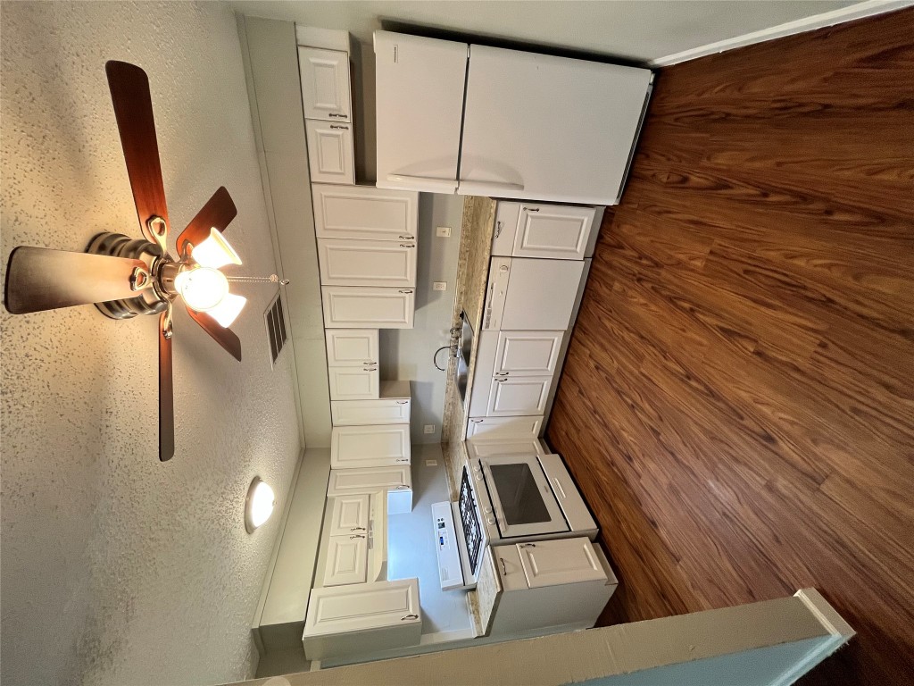 4906 West Gate Boulevard, Unit 104 Austin, TX 78745 - Photo 1 of 22 Kitchen featuring white cabinets, refrigerator, light countertops, range, and dark wood-type flooring
