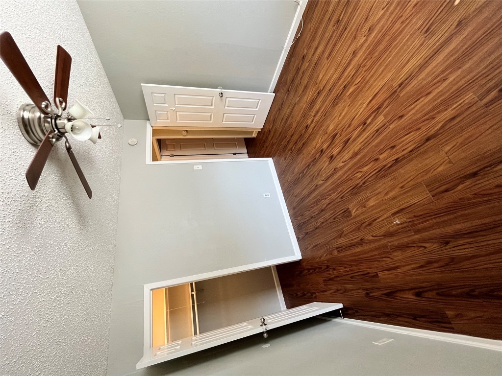 4906 West Gate Boulevard, Unit 104 Austin, TX 78745 - Photo 12 of 22 Unfurnished bedroom featuring a spacious closet, dark wood-style flooring, a textured ceiling, and ceiling fan