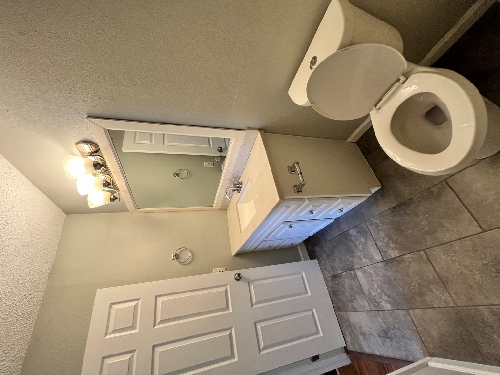 4906 West Gate Boulevard, Unit 104 Austin, TX 78745 - Photo 16 of 22 Half bath with vanity, a textured ceiling, dark tile patterned floors, and a textured wall