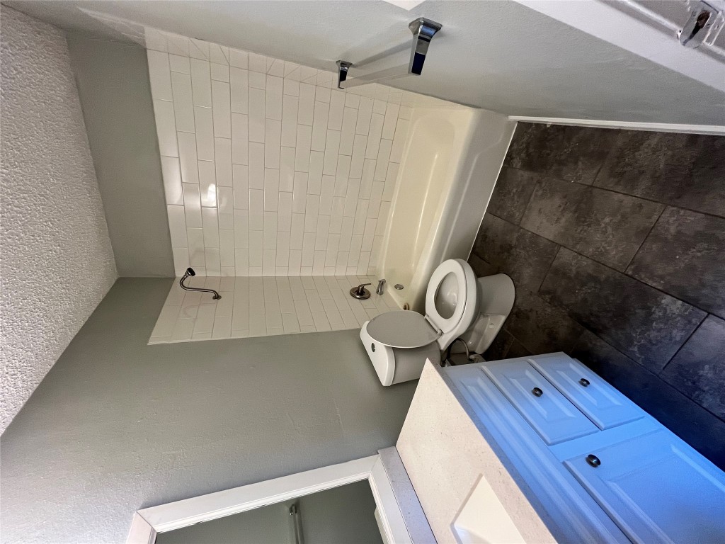 4906 West Gate Boulevard, Unit 104 Austin, TX 78745 - Photo 17 of 22 Bathroom with shower / tub combination, vanity, a textured ceiling, a textured wall, and dark tile patterned floors
